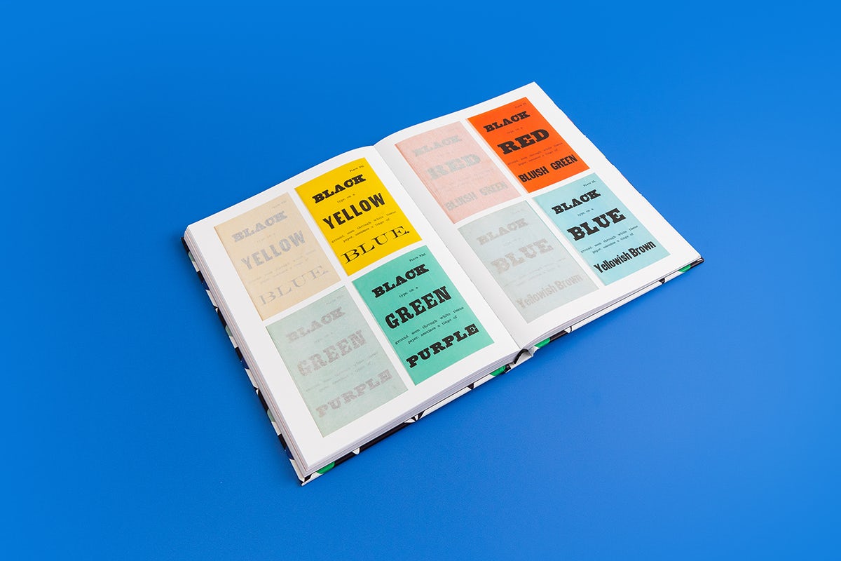 L'image montre une page à l'intérieur du livre Histoire de la couleur, montrant quatre affiches en jaune, vert, rouge et bleu, à côté des versions estompées de chaque affiche.  Le livre est disposé sur un fond bleu vif