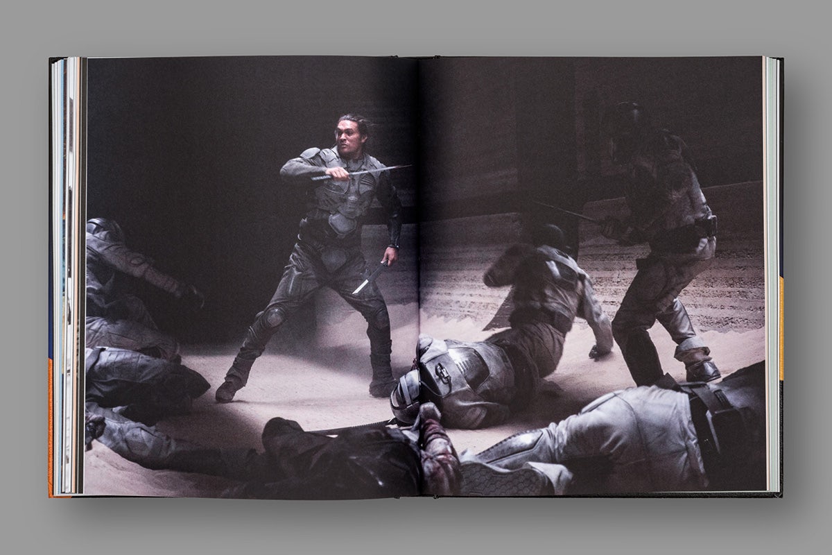 Image d'une double page d'un livre sur Dune, présentant une photographie en double page d'une personne combattant une foule qui l'entoure.