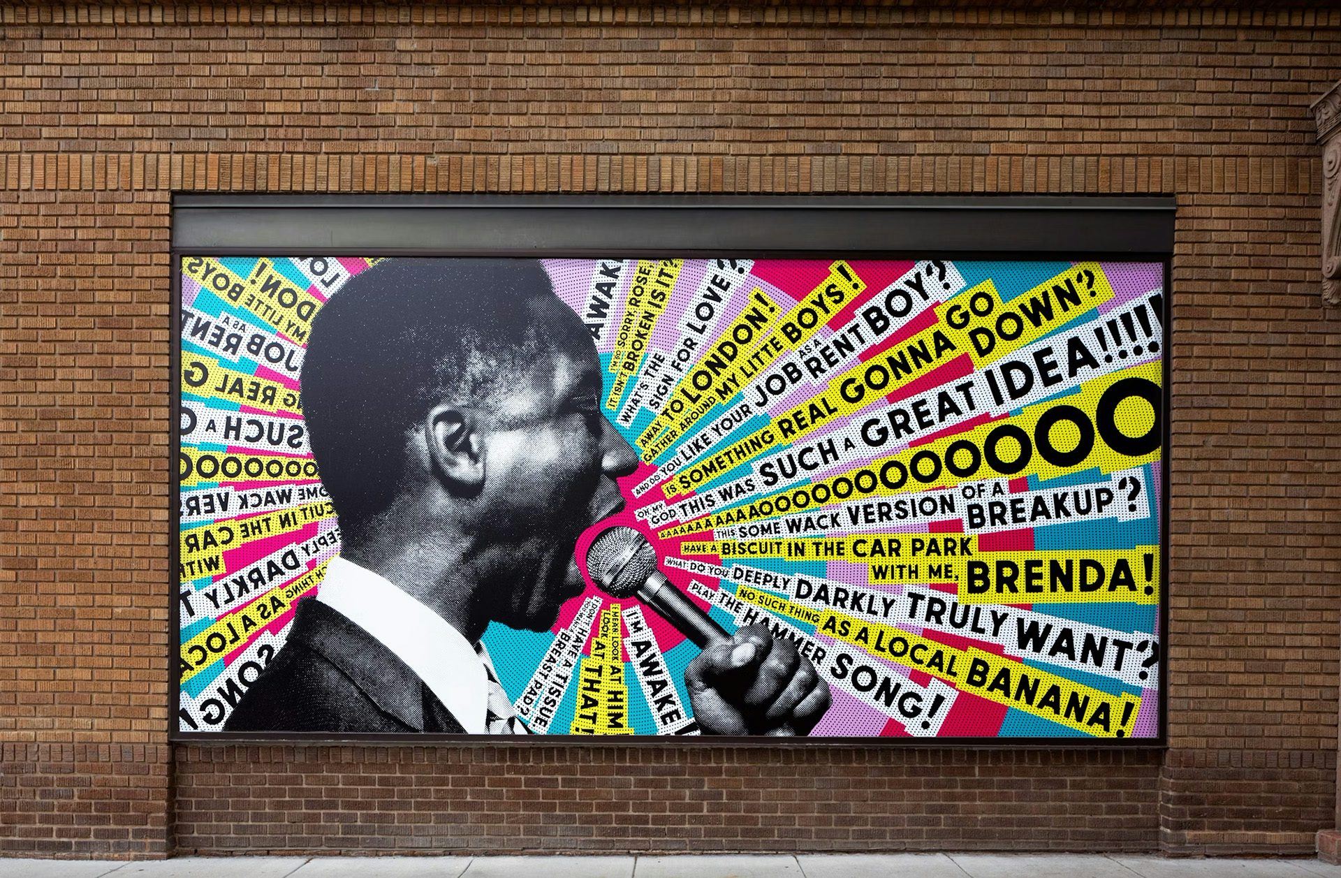 Affiche du Studio Theatre affichée sur un mur de briques présentant une photo en noir et blanc d'une personne parlant dans un microphone avec des lignes colorées de texte rayonnant du microphone
