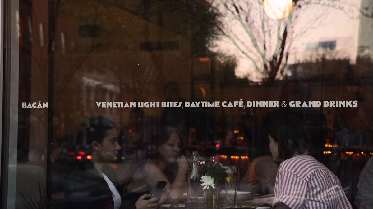Une vitrine de restaurant affichant la ligne « Bouchées légères vénitiennes, café de jour, dîner et grandes boissons »