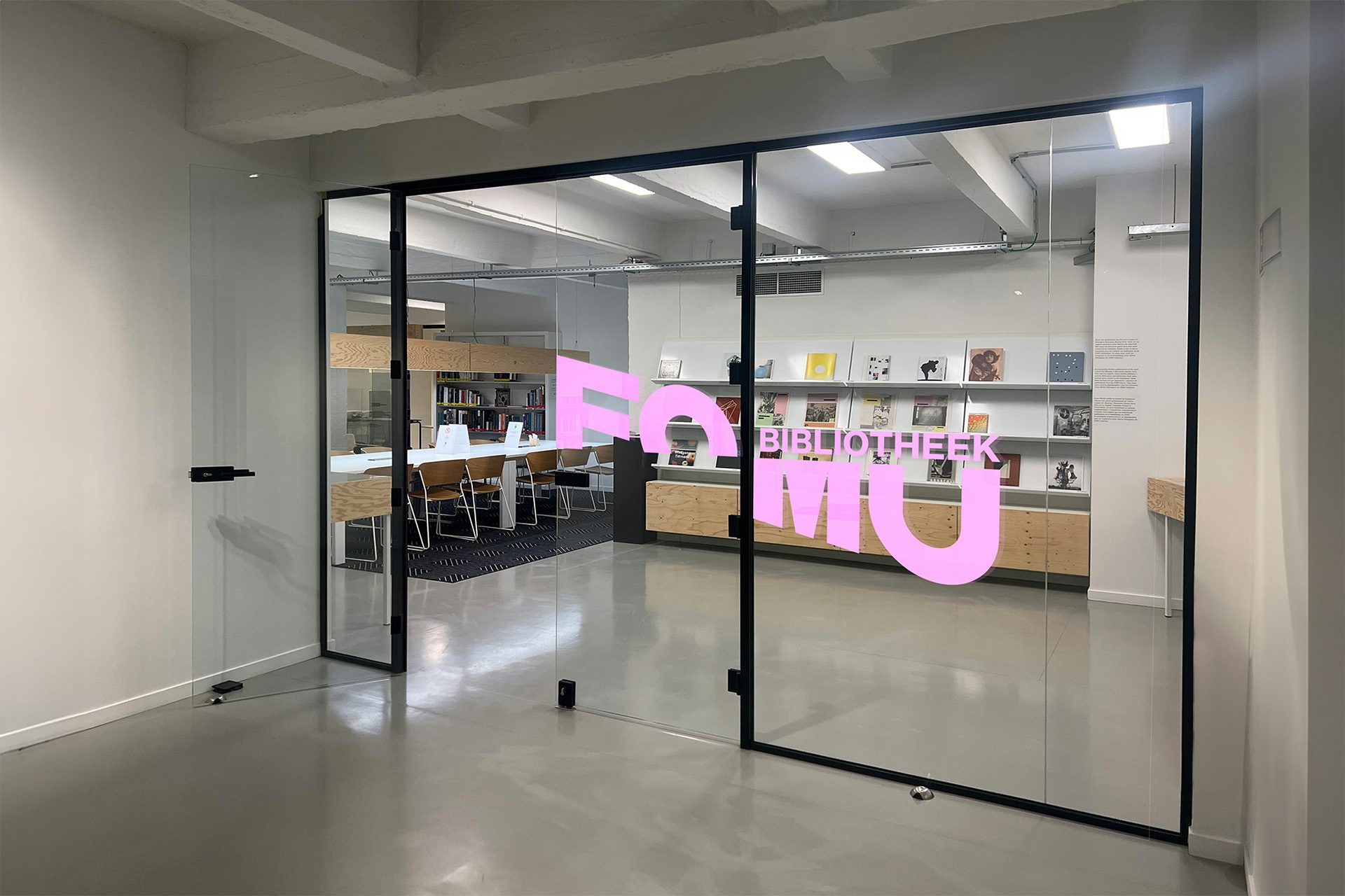 L'espace de la bibliothèque de Fomu vu à travers des portes transparentes comportant le mot-symbole de Fomu tranché en diagonale