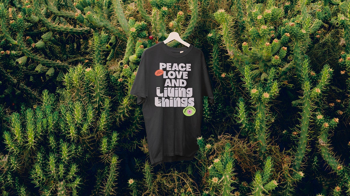 T-shirt noir avec l'inscription « Paix, amour et êtres vivants » sur un fond de feuilles