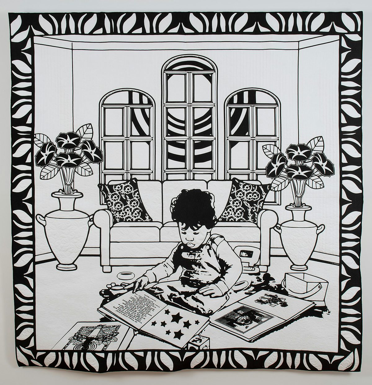 Couette noire et blanche représentant un enfant lisant des livres sur le sol d'un salon